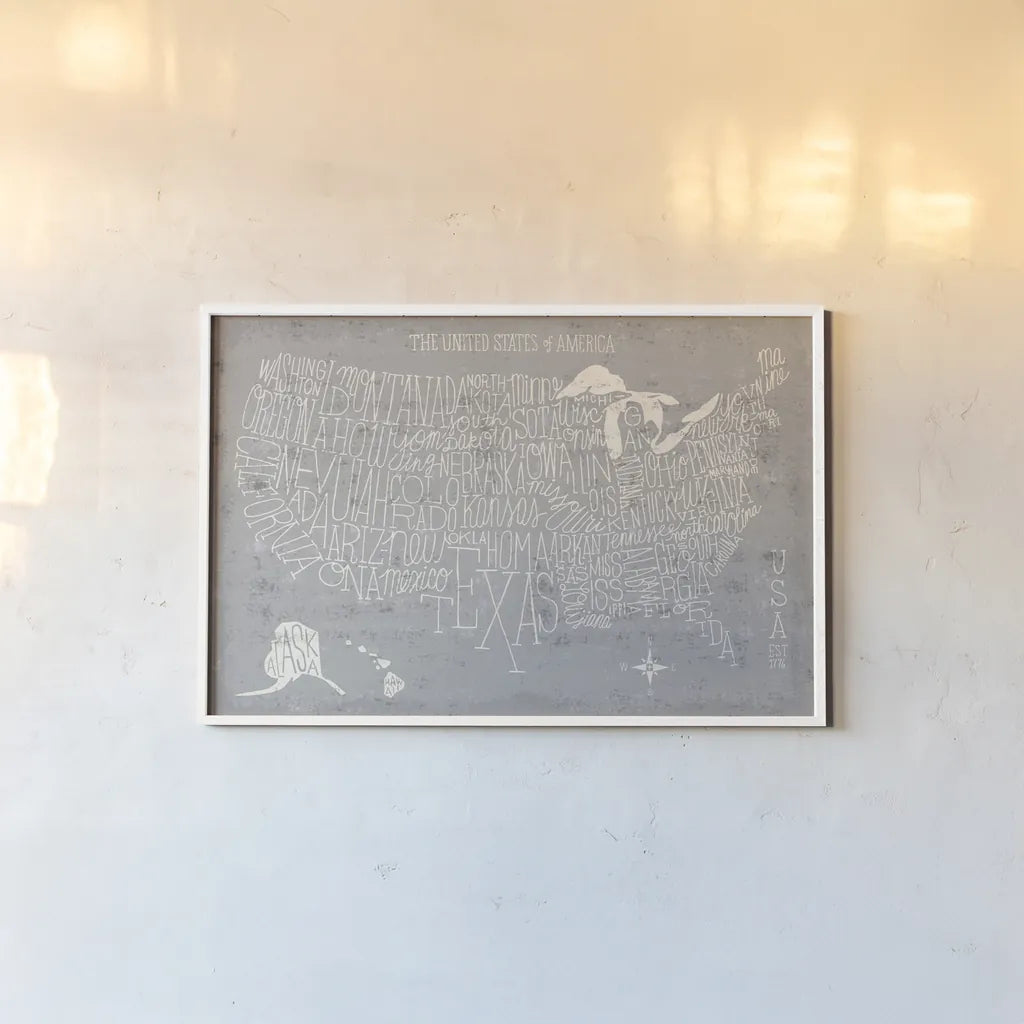 Hand Lettered USA Map Gray by Michael Mullan. shown as a paper print in a white frame. Available as a archival giclee rolled canvas, fine art paper, or poster print. SKU 43245i.
