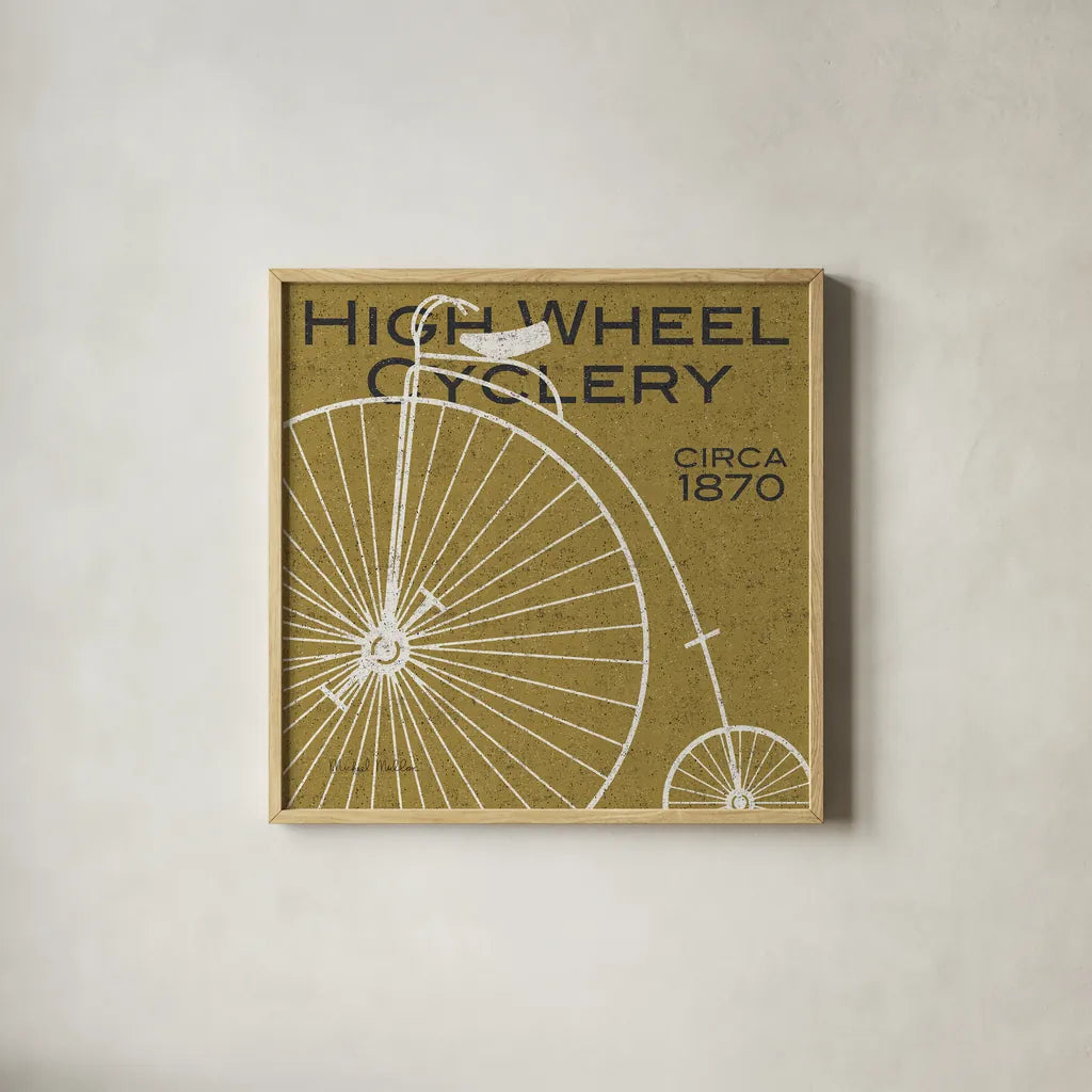 High Wheel Cyclery by Michael Mullan. Shown in a natural wood glass frame for a timeless modern aesthetic. Available as an archival giclee rolled canvas, fine art paper, or poster print. SKU 11869a.