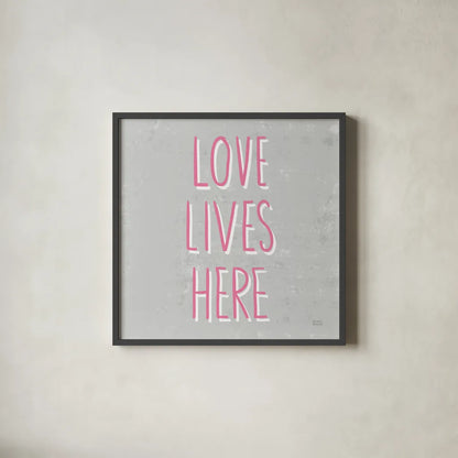 Love Lives Here Slate and Pink by Michael Mullan. Shown in a sleek black glass frame for a contemporary gallery look. Available as an archival giclee rolled canvas, fine art paper, or poster print. SKU 67444a.