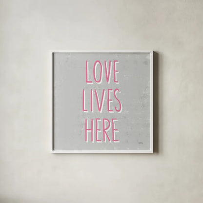 Love Lives Here Slate and Pink by Michael Mullan. Shown in a crisp white glass frame for a clean and minimalist style. Available as an archival giclee rolled canvas, fine art paper, or poster print. SKU 67444a.