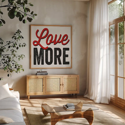 Love More on White by Michael Mullan. Shown in a natural wood frame in a cozy modern living room. Available as an archival giclee rolled canvas, fine art paper, or poster print. SKU 30984a.