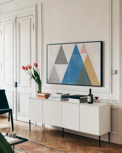 Mod Triangles I Gray by Michael Mullan. shown as a framed stretched canvas in a living room above a console. Available as a archival giclee rolled canvas, fine art paper, or poster print. SKU 42833i.
