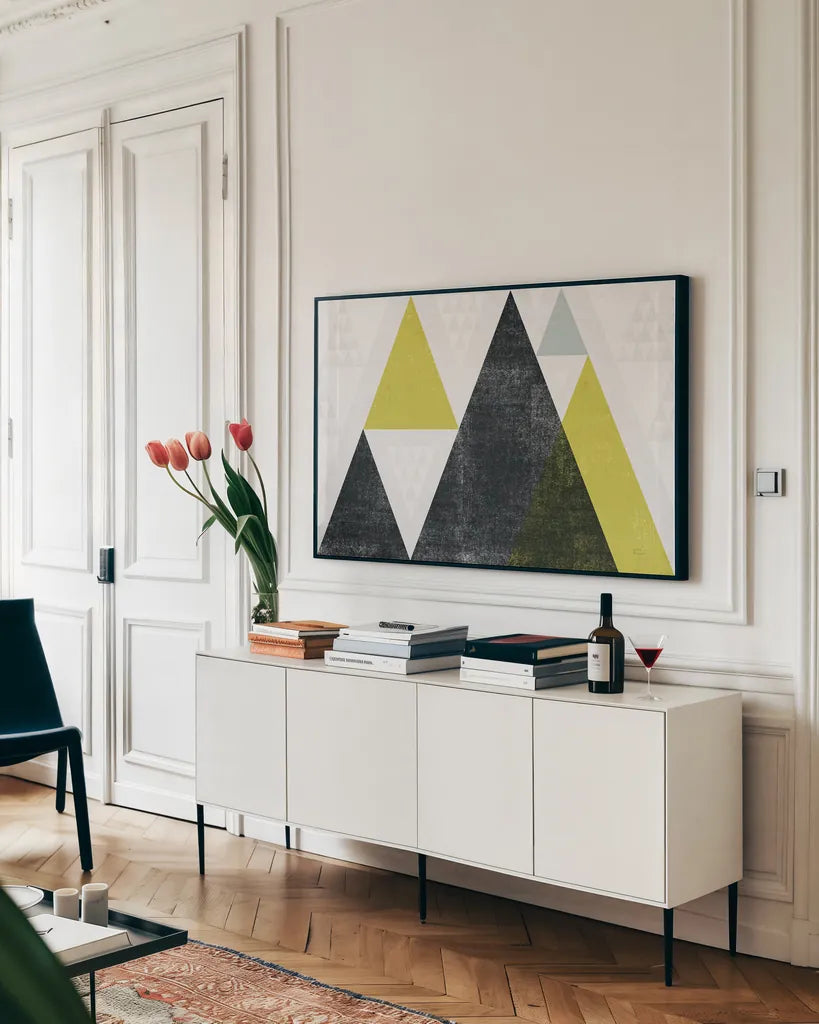 Mod Triangles I Yellow Black by Michael Mullan. shown as a framed stretched canvas in a living room above a console. Available as a archival giclee rolled canvas, fine art paper, or poster print. SKU 64127i.