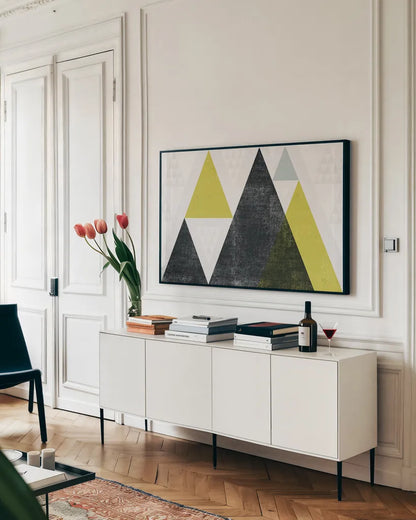 Mod Triangles I Yellow Black by Michael Mullan. shown as a framed stretched canvas in a living room above a console. Available as a archival giclee rolled canvas, fine art paper, or poster print. SKU 64127i.