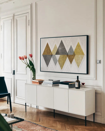 Mod Triangles II Gold by Michael Mullan. shown as a framed stretched canvas in a living room above a console. Available as a archival giclee rolled canvas, fine art paper, or poster print. SKU 22302i.