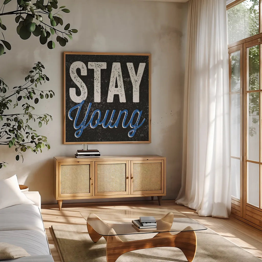 Stay Young by Michael Mullan. Shown in a natural wood frame in a cozy modern living room. Available as an archival giclee rolled canvas, fine art paper, or poster print. SKU 13852a.
