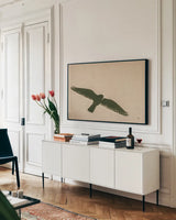 American Kestrel Hunting by Nathan Larson. shown as a framed stretched canvas in a living room above a console. Available as a archival giclee rolled canvas, fine art paper, or poster print. SKU 92578i.