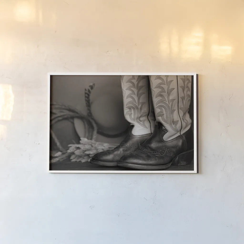 Cowboy Boots XI BW by Nathan Larson. shown as a paper print in a white frame. Available as a archival giclee rolled canvas, fine art paper, or poster print. SKU 82741i.