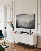 Glacier National Park Gateway BW by Nathan Larson. shown as a framed stretched canvas in a living room above a console. Available as a archival giclee rolled canvas, fine art paper, or poster print. SKU 87647i.