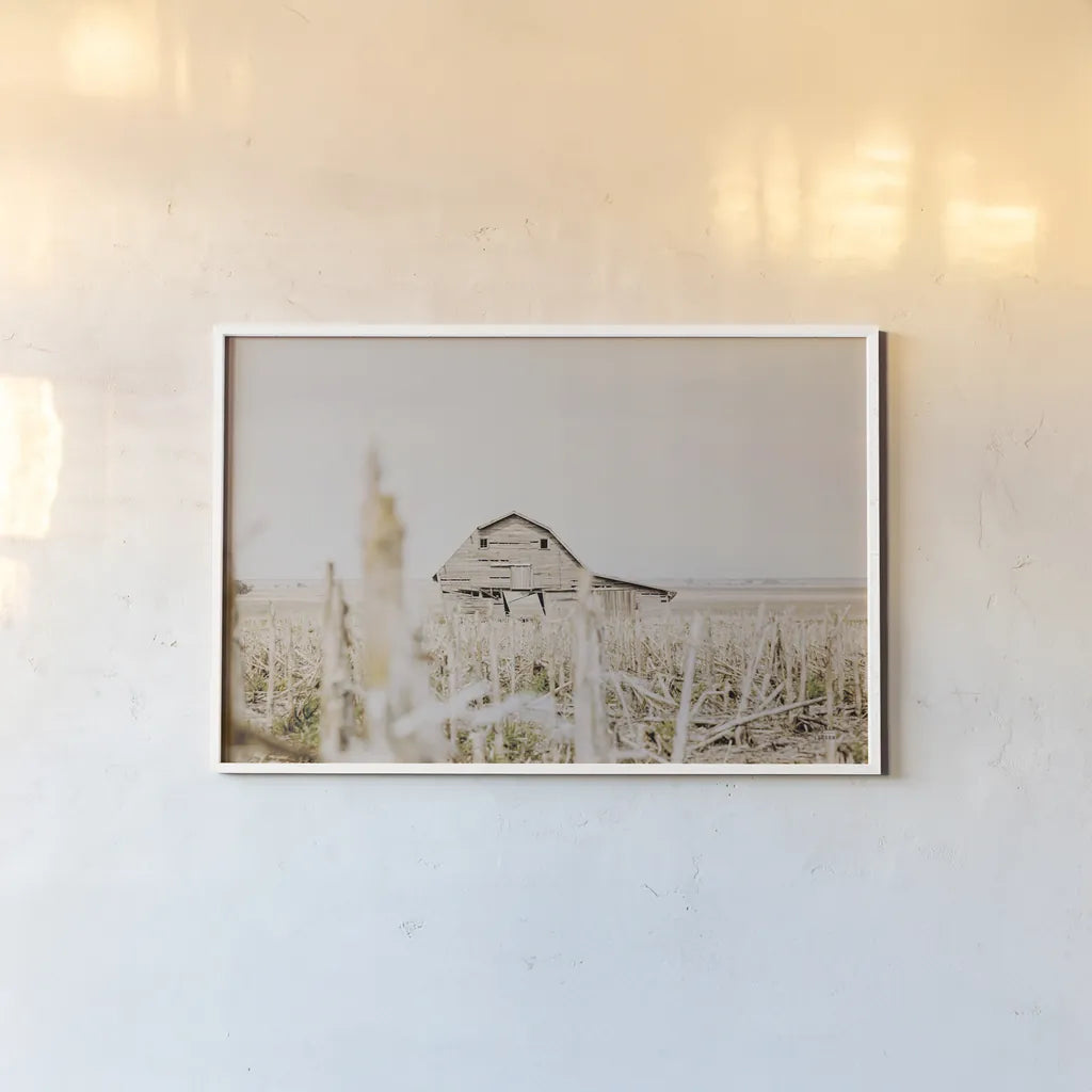 Leaning Barn Field I by Nathan Larson. shown as a paper print in a white frame. Available as a archival giclee rolled canvas, fine art paper, or poster print. SKU 86060i.