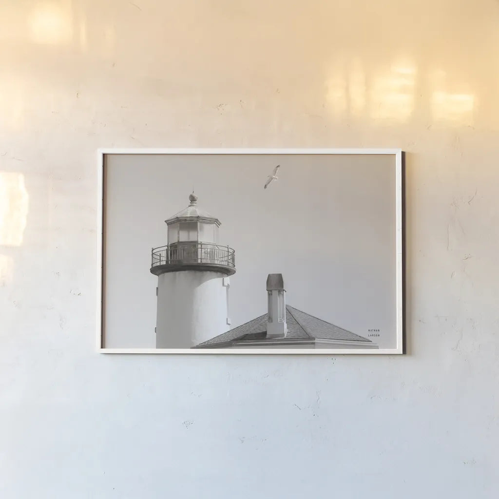 Lighthouse Fly Over by Nathan Larson. shown as a paper print in a white frame. Available as a archival giclee rolled canvas, fine art paper, or poster print. SKU 87193i.