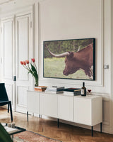 Longhorn Evening by Nathan Larson. shown as a framed stretched canvas in a living room above a console. Available as a archival giclee rolled canvas, fine art paper, or poster print. SKU 91378i.