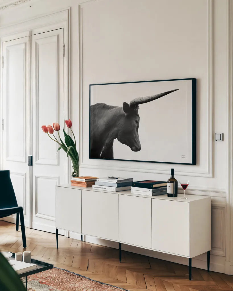 Longhorn Sunset Graze BW by Nathan Larson. shown as a framed stretched canvas in a living room above a console. Available as a archival giclee rolled canvas, fine art paper, or poster print. SKU 92290i.