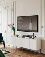 Low Point Lighthouse by Nathan Larson. shown as a framed stretched canvas in a living room above a console. Available as a archival giclee rolled canvas, fine art paper, or poster print. SKU 100499i.