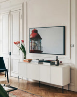 Low Point Lighthouse View by Nathan Larson. shown as a framed stretched canvas in a living room above a console. Available as a archival giclee rolled canvas, fine art paper, or poster print. SKU 100498i.