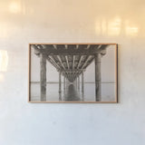 Pacific Pier by Nathan Larson. shown as a paper print in a natural frame. Available as a archival giclee rolled canvas, fine art paper, or poster print. SKU 86918i.