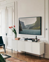 Western Brook Pond by Nathan Larson. shown as a framed stretched canvas in a living room above a console. Available as a archival giclee rolled canvas, fine art paper, or poster print. SKU 101660i.