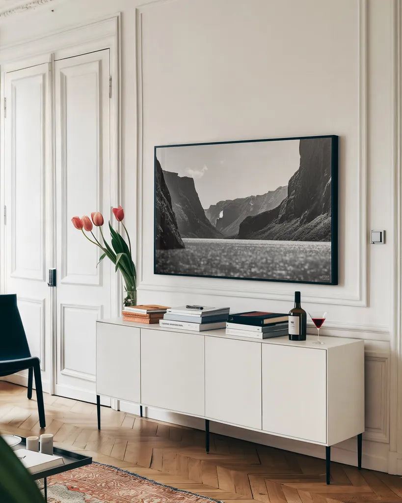 Western Brook Pond BW by Nathan Larson. shown as a framed stretched canvas in a living room above a console. Available as a archival giclee rolled canvas, fine art paper, or poster print. SKU 101662i.