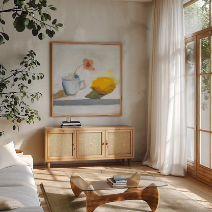 Lemon and Cup by Pamela Munger. Shown in a natural wood frame in a cozy modern living room. Available as an archival giclee rolled canvas, fine art paper, or poster print. SKU 96979a.