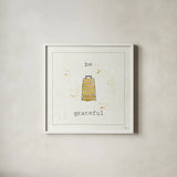 Cuisine Cuties Be Grateful by Pela Studio. Shown in a crisp white glass frame for a clean and minimalist style. Available as an archival giclee rolled canvas, fine art paper, or poster print. SKU 28477a.