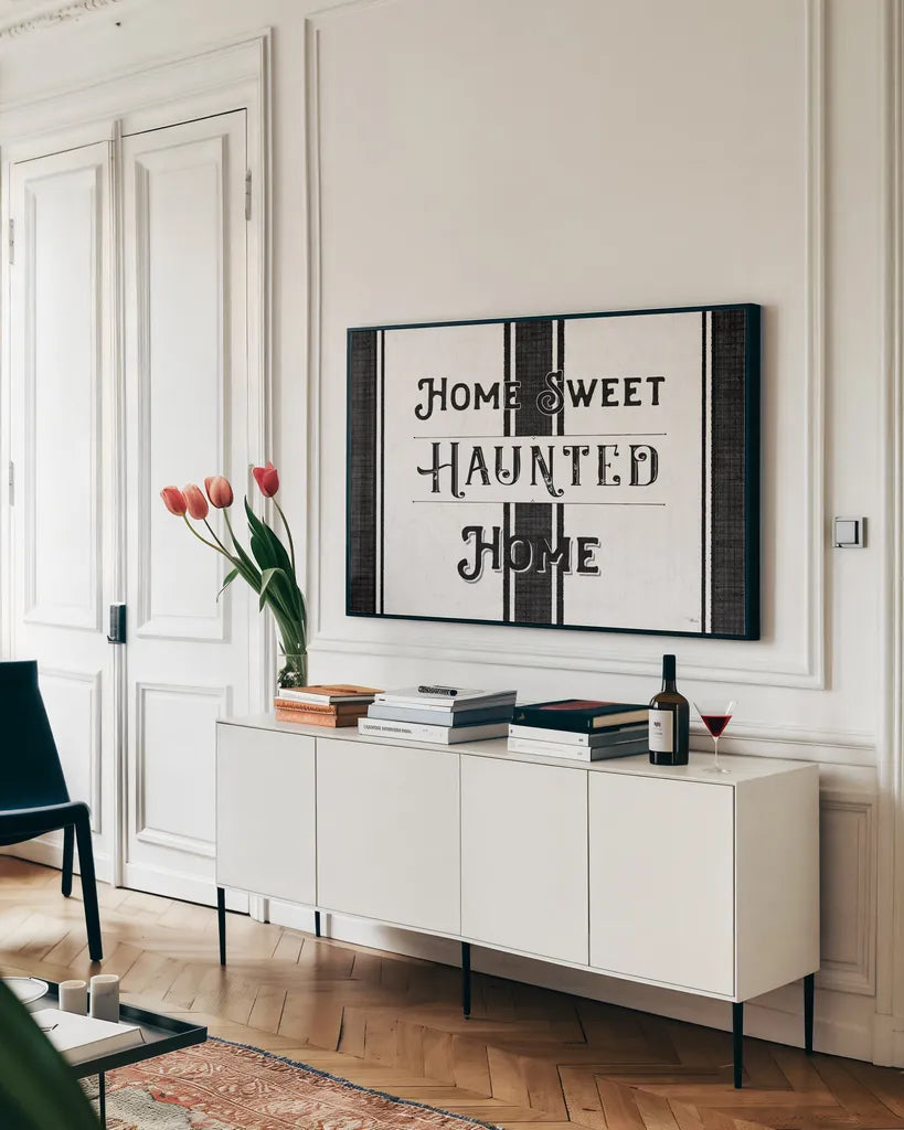 Home Sweet Haunted Home BW by Pela Studio. shown as a framed stretched canvas in a living room above a console. Available as a archival giclee rolled canvas, fine art paper, or poster print. SKU 68426i.