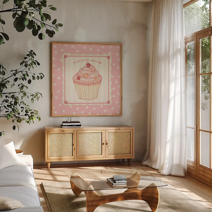 Lil Cupcakes Pink III by Pela Studio. Shown in a natural wood frame in a cozy modern living room. Available as an archival giclee rolled canvas, fine art paper, or poster print. SKU 100985a.