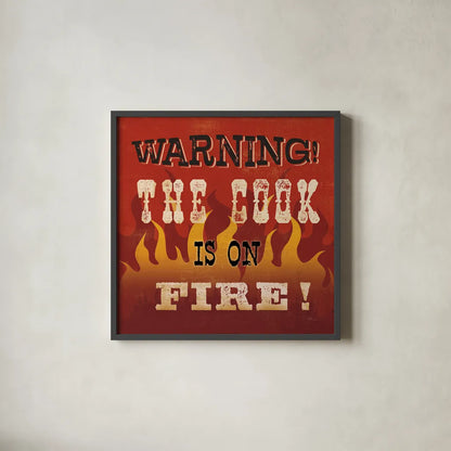 The Cook is On Fire by Pela Studio. Shown in a sleek black glass frame for a contemporary gallery look. Available as an archival giclee rolled canvas, fine art paper, or poster print. SKU 92148a.