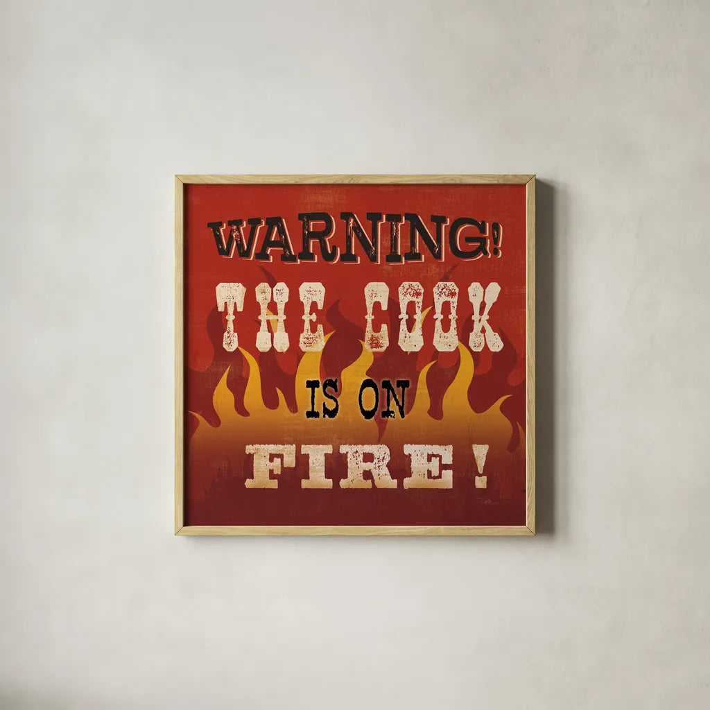 The Cook is On Fire by Pela Studio. Shown in a natural wood glass frame for a timeless modern aesthetic. Available as an archival giclee rolled canvas, fine art paper, or poster print. SKU 92148a.