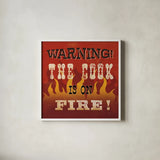 The Cook is On Fire by Pela Studio. Shown in a crisp white glass frame for a clean and minimalist style. Available as an archival giclee rolled canvas, fine art paper, or poster print. SKU 92148a.