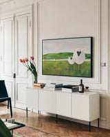 Sheep in the Meadow by Phyllis Adams. shown as a framed stretched canvas in a living room above a console. Available as a archival giclee rolled canvas, fine art paper, or poster print. SKU 27254i.