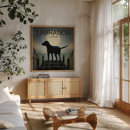 Moonrise Black Dog - Labrador Lake by Ryan Fowler. Shown in a natural wood frame in a cozy modern living room. Available as an archival giclee rolled canvas, fine art paper, or poster print. SKU 11454a.