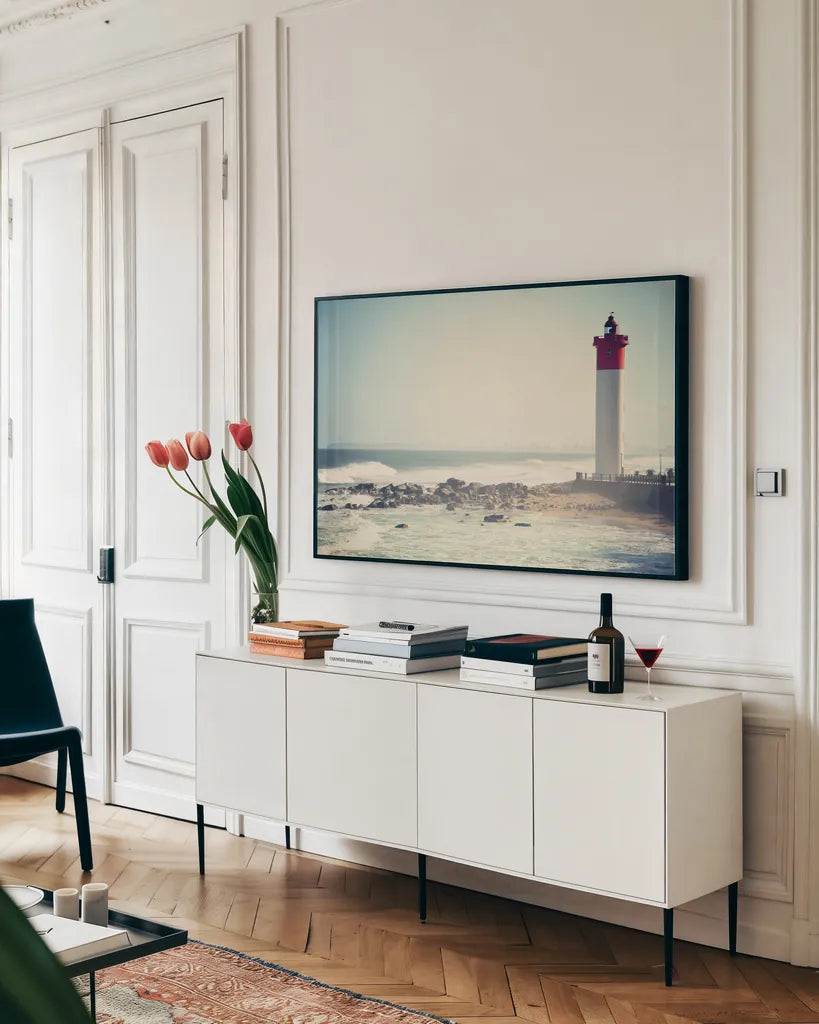 Umhlanga Lighthouse by Sharon Vardy. shown as a framed stretched canvas in a living room above a console. Available as a archival giclee rolled canvas, fine art paper, or poster print. SKU 93121i.