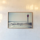 Umhlanga Lighthouse by Sharon Vardy. shown as a paper print in a natural frame. Available as a archival giclee rolled canvas, fine art paper, or poster print. SKU 93121i.
