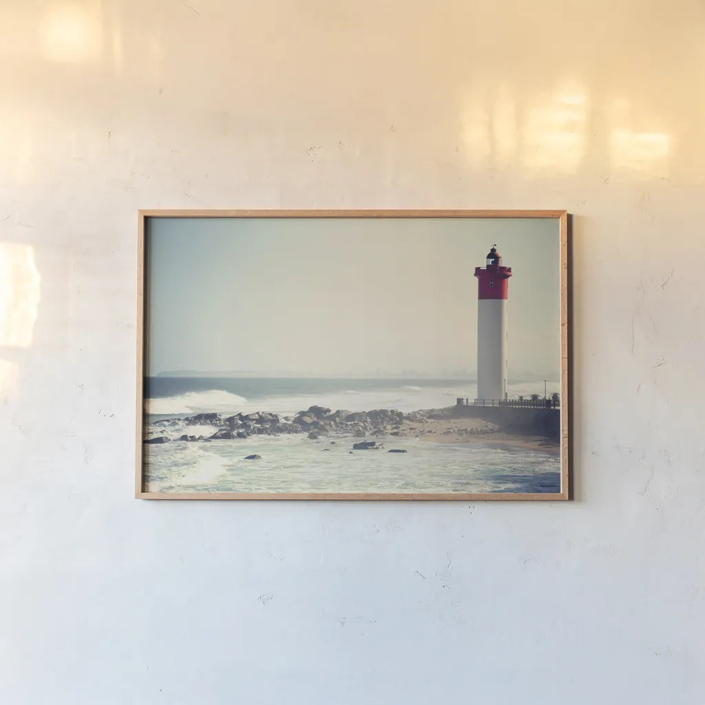Umhlanga Lighthouse by Sharon Vardy. shown as a paper print in a natural frame. Available as a archival giclee rolled canvas, fine art paper, or poster print. SKU 93121i.