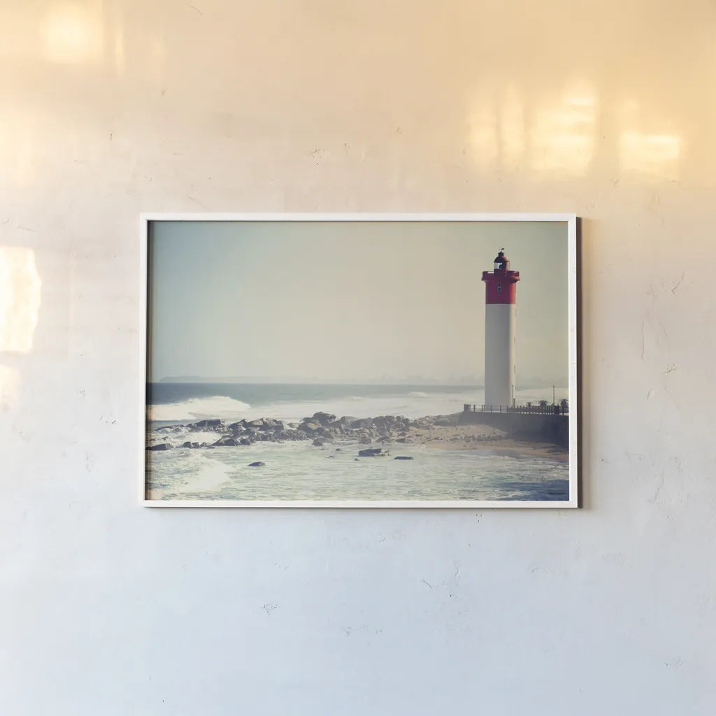 Umhlanga Lighthouse by Sharon Vardy. shown as a paper print in a white frame. Available as a archival giclee rolled canvas, fine art paper, or poster print. SKU 93121i.