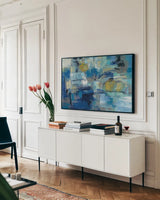 Ultramarine Waves III by Silvia Vassileva. shown as a framed stretched canvas in a living room above a console. Available as a archival giclee rolled canvas, fine art paper, or poster print. SKU 24576i.