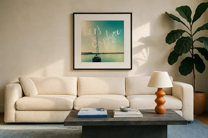 Coastline Sailboat Explore by Sue Schlabach. Displayed in a glass frame with matte in a clean modern living room. Available as an archival giclee rolled canvas, fine art paper, or poster print. SKU 15251a.