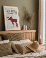 Northern Trading Moose Feed v2 by Sue Schlabach. shown as a paper print in a natural frame. Available as a archival giclee rolled canvas, fine art paper, or poster print. SKU 65049h.