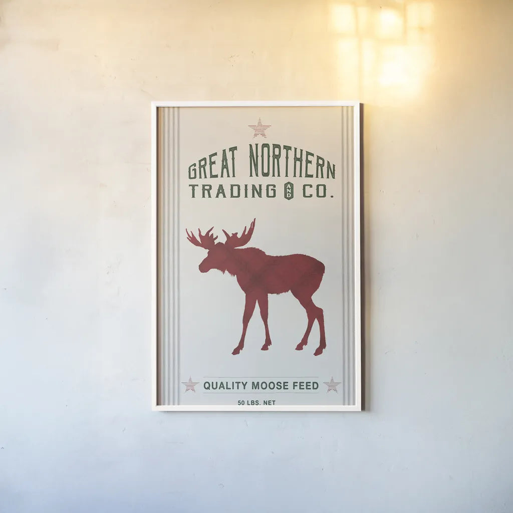 Northern Trading Moose Feed v2 by Sue Schlabach. shown as a paper print in a white frame. Available as a archival giclee rolled canvas, fine art paper, or poster print. SKU 65049h.