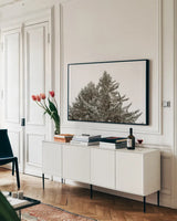 Snow on Treetops by Sue Schlabach. shown as a framed stretched canvas in a living room above a console. Available as a archival giclee rolled canvas, fine art paper, or poster print. SKU 60939i.