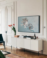 Magnolia Branch by Wellington Studio. shown as a framed stretched canvas in a living room above a console. Available as a archival giclee rolled canvas, fine art paper, or poster print. SKU 89443i.