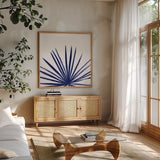 Statement Palms III Indigo by Wellington Studio. Shown in a natural wood frame in a cozy modern living room. Available as an archival giclee rolled canvas, fine art paper, or poster print. SKU 34075a.