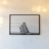 Brooklyn Bridge From Below by Wild Apple Portfolio. shown as a paper print in a black flame. Available as a archival giclee rolled canvas, fine art paper, or poster print. SKU 67630i.