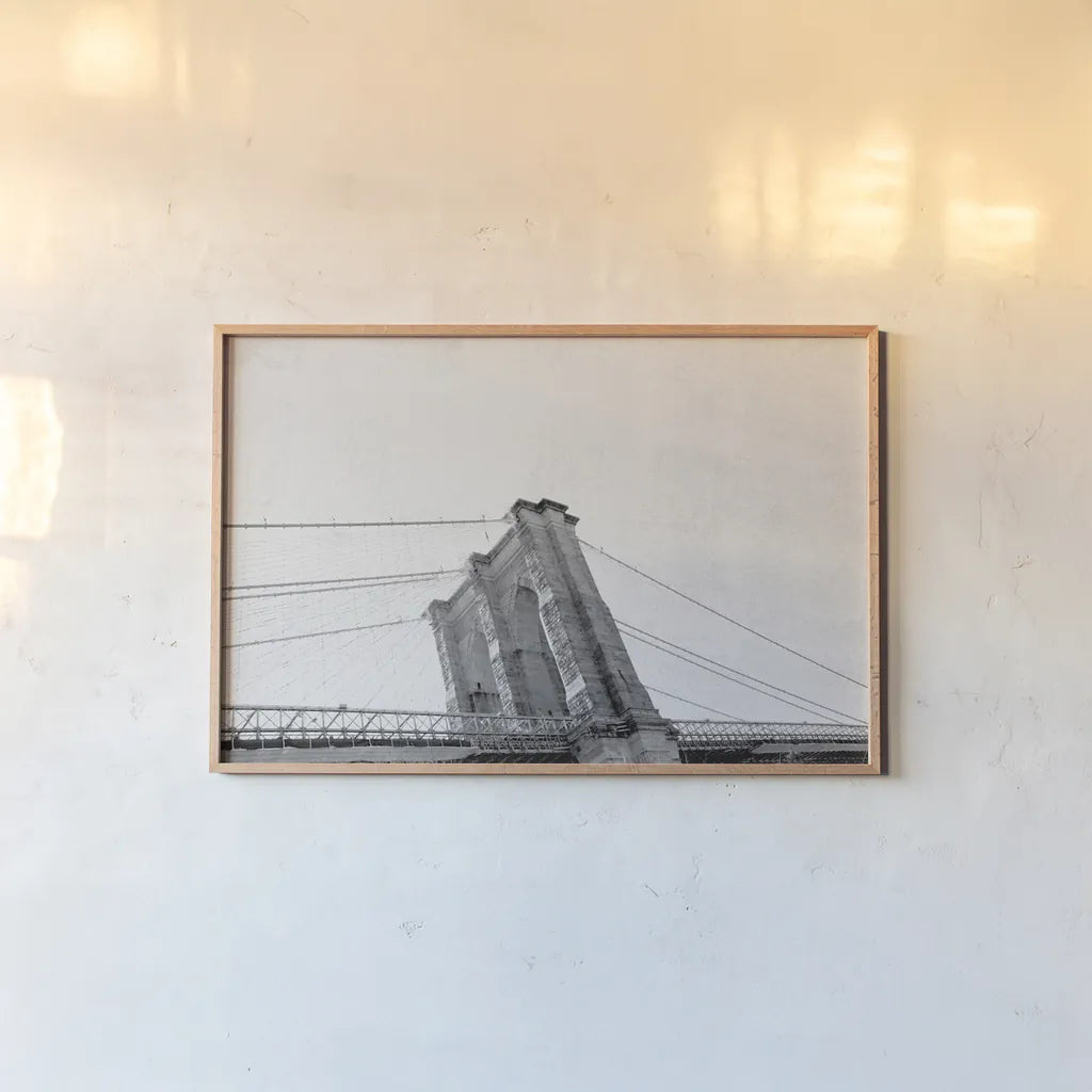 Brooklyn Bridge From Below by Wild Apple Portfolio. shown as a paper print in a natural frame. Available as a archival giclee rolled canvas, fine art paper, or poster print. SKU 67630i.
