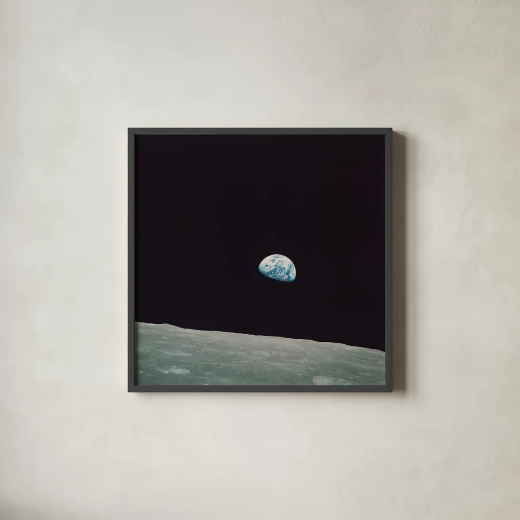 First Earth Rise by Wild Apple Portfolio. Shown in a sleek black glass frame for a contemporary gallery look. Available as an archival giclee rolled canvas, fine art paper, or poster print. SKU 84536a.