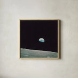 First Earth Rise by Wild Apple Portfolio. Shown in a natural wood glass frame for a timeless modern aesthetic. Available as an archival giclee rolled canvas, fine art paper, or poster print. SKU 84536a.