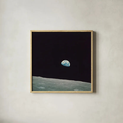 First Earth Rise by Wild Apple Portfolio. Shown in a natural wood glass frame for a timeless modern aesthetic. Available as an archival giclee rolled canvas, fine art paper, or poster print. SKU 84536a.