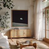 First Earth Rise by Wild Apple Portfolio. Shown in a natural wood frame in a cozy modern living room. Available as an archival giclee rolled canvas, fine art paper, or poster print. SKU 84536a.