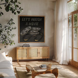 Lets Watch a Movie by Wild Apple Portfolio. Shown in a natural wood frame in a cozy modern living room. Available as an archival giclee rolled canvas, fine art paper, or poster print. SKU 21553a.
