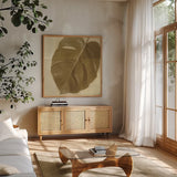 Monstera Leaf I by Wild Apple Portfolio. Shown in a natural wood frame in a cozy modern living room. Available as an archival giclee rolled canvas, fine art paper, or poster print. SKU 37205a.